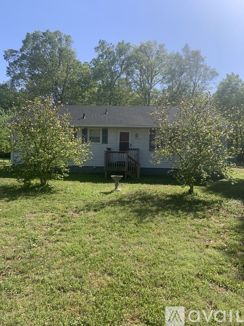 A house with a white picket fence and a tree in front of it.