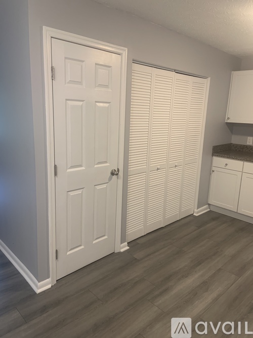A white door is in a room with a wooden floor.