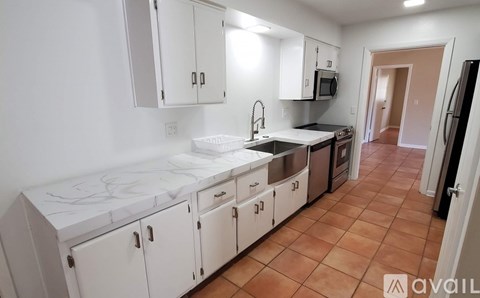 A kitchen with white cabinets and a tiled floor.