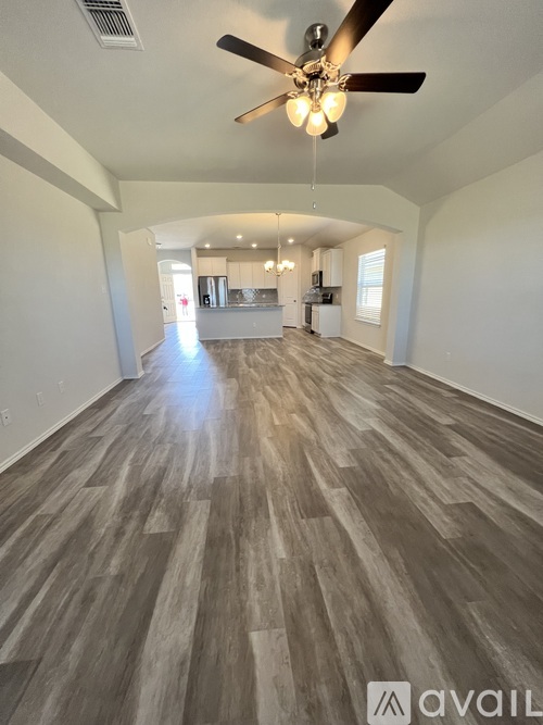 A spacious room with wooden flooring and a ceiling fan.