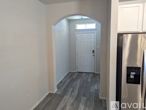A kitchen with a refrigerator and a door in the background.