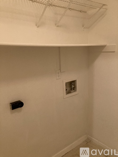 A white wall with a shelf and a picture hanging on it.
