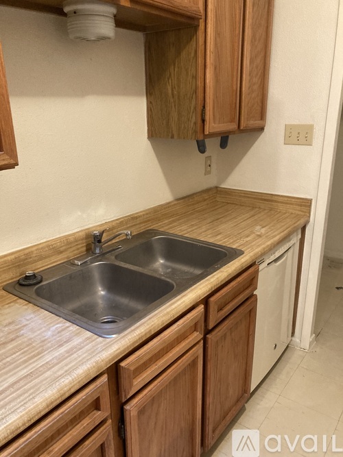 A kitchen with wooden cabinets and a stainless steel sink.