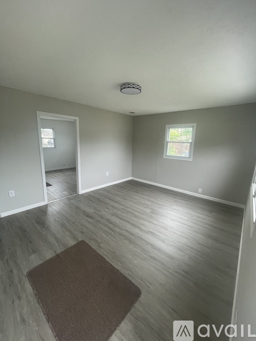 A room with a brown rug on the wooden floor.