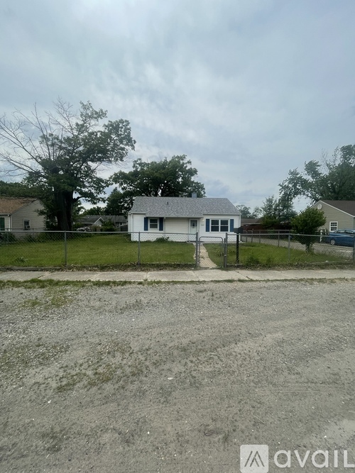 A house with a white fence and a gravel driveway in front.
