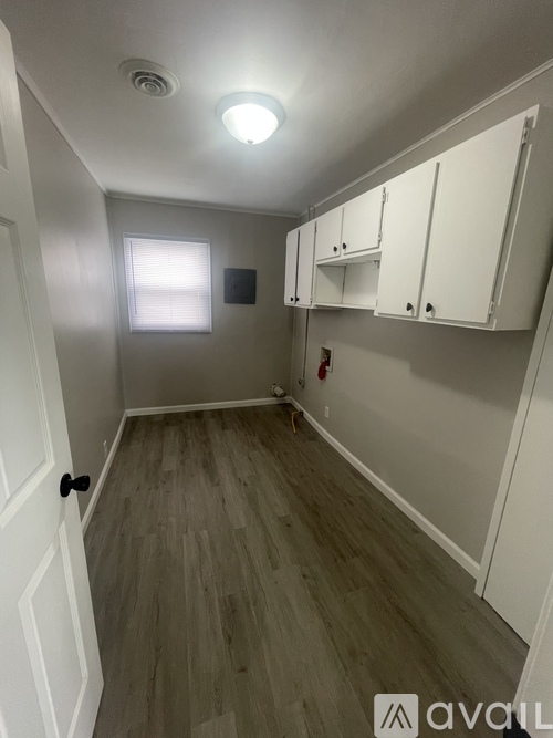 A room with white cabinets and a wood floor.