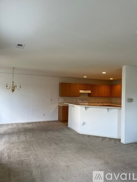 A spacious kitchen with wooden cabinets and a chandelier.