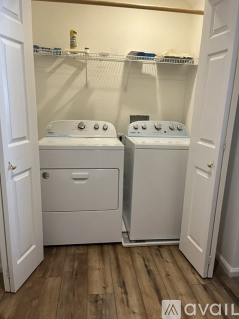 A small laundry room with two washing machines and a shelf above them.