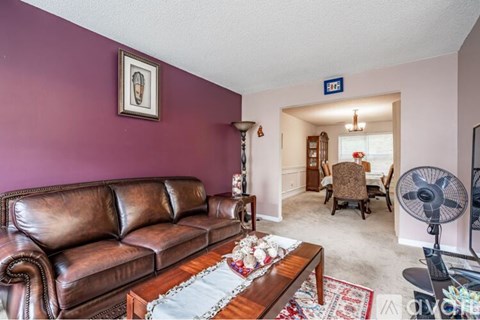 A living room with a brown leather couch and a coffee table with a rug on it.