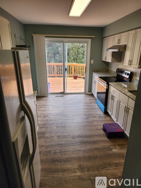A kitchen with a refrigerator on the left and a view of a deck outside.