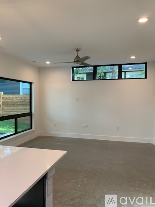 A room with a ceiling fan and a window with a view of a building.