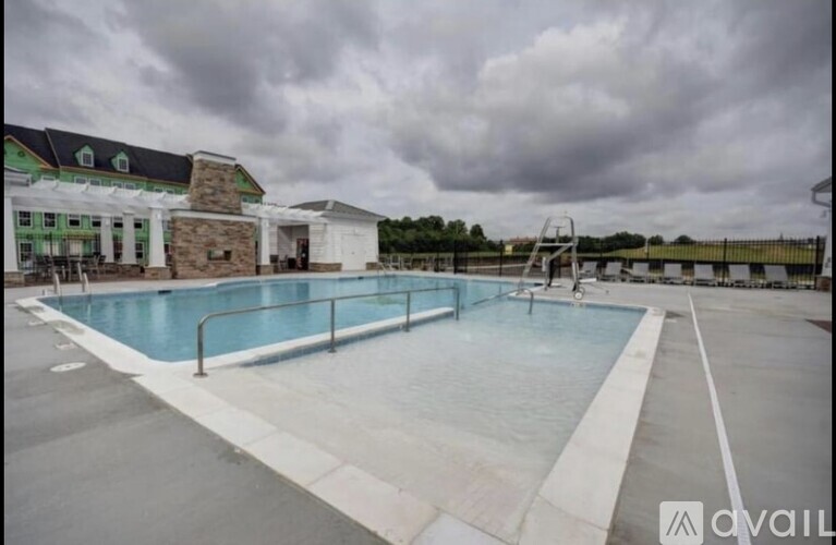 A large outdoor swimming pool with a diving board and a building in the background.