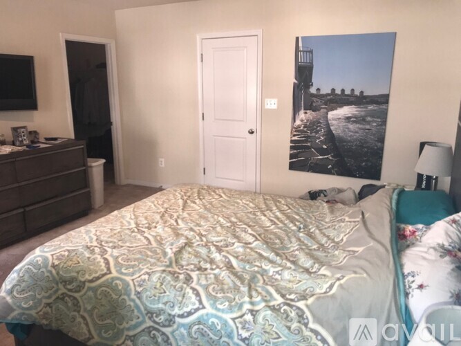 A bedroom with a large bed and a painting on the wall.