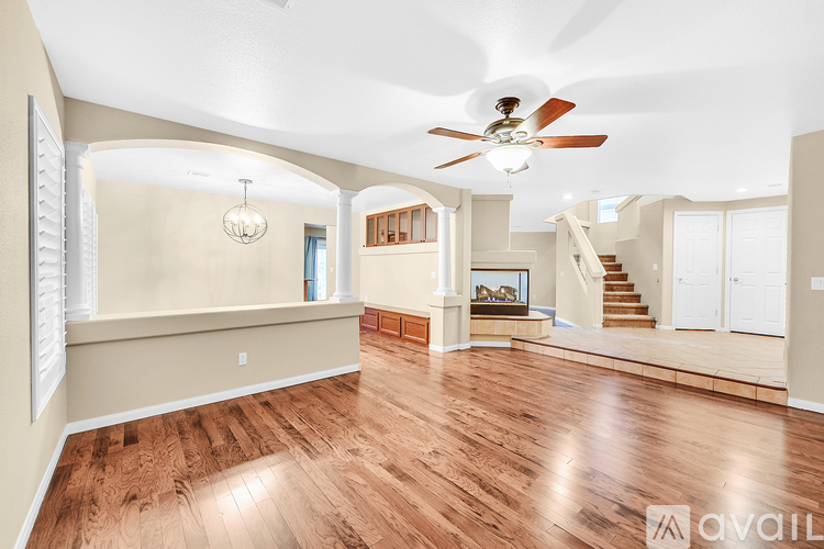 A spacious room with wood flooring and a ceiling fan.