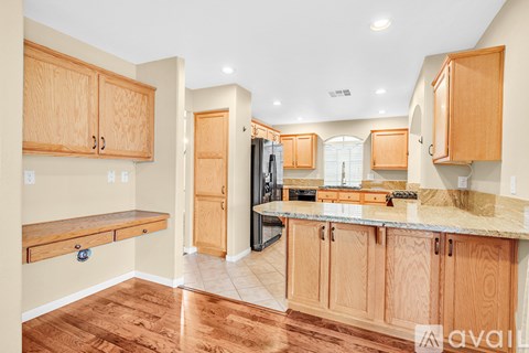A kitchen with wooden cabinets and a marble countertop.