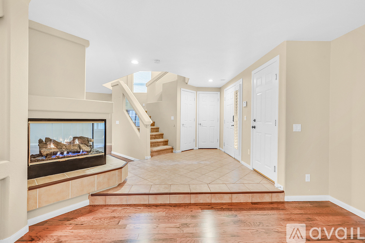 A spacious living room with a fireplace and a staircase.