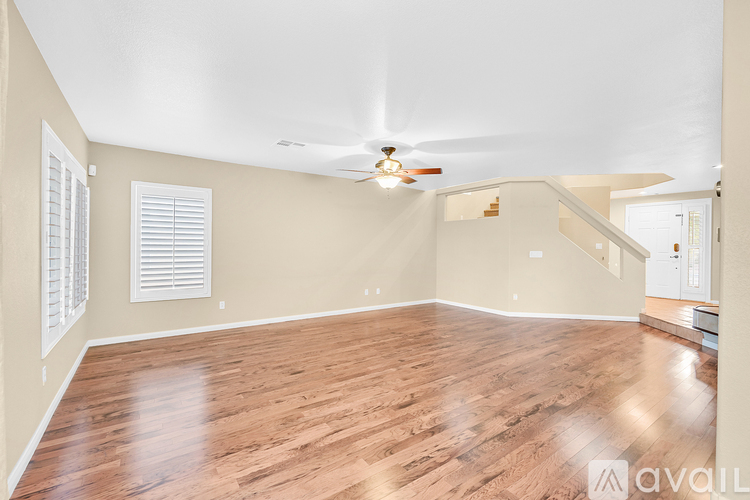 A spacious room with wooden flooring and a ceiling fan.