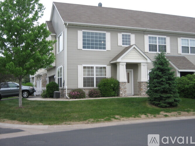A grey house with a tree in front of it.