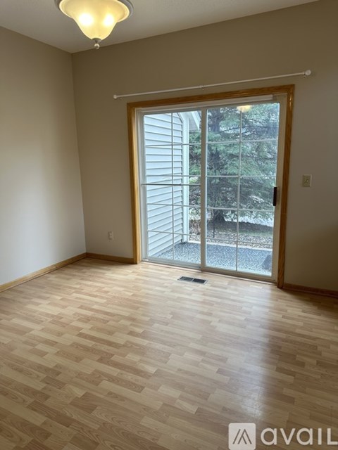 A room with wooden flooring and a sliding glass door leading outside.