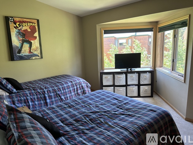 A bedroom with two beds and a Superman poster on the wall.