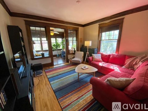 A living room with a red couch and a wooden floor.