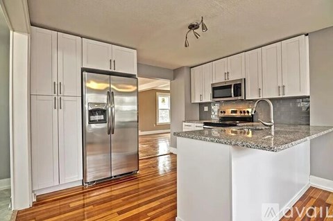 A kitchen with a refrigerator, microwave, and stove top oven.