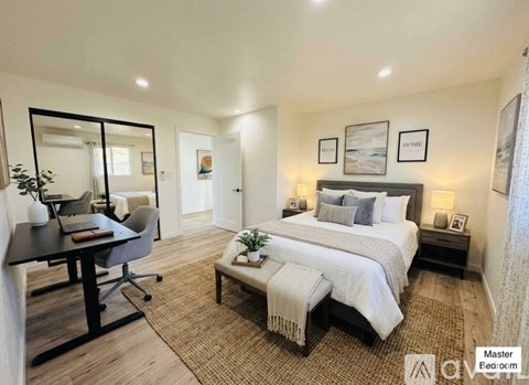 A bedroom with a large bed, a desk with a chair, and a mirror on the wall.