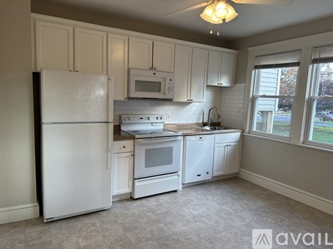 A kitchen with white appliances and cabinets.