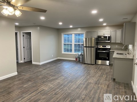 A spacious kitchen and living room with wood flooring and a ceiling fan.