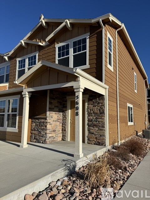 A house with brown siding and a stone pillar in front.