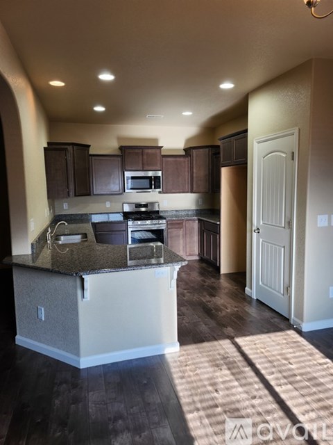 A kitchen with brown cabinets and a granite countertop.