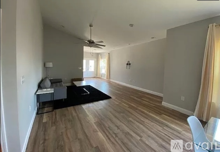 A spacious room with wooden flooring and a ceiling fan.