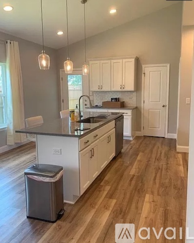A kitchen with white cabinets and a wooden floor.