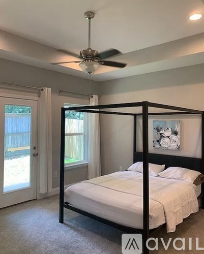 A bedroom with a four-poster bed and a ceiling fan.