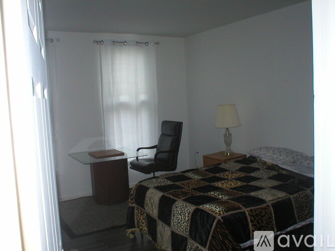 A bedroom with a bed, chair, and desk.