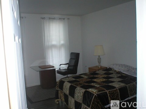 A bedroom with a bed, chair, and desk.