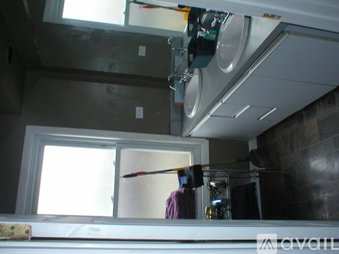 A man is painting a wall in a room with a window.