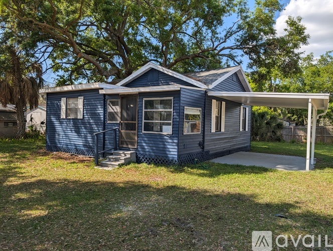 A blue house with a porch and a tree in front.
