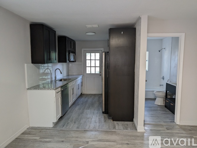 A kitchen with a refrigerator, sink, and cabinets.