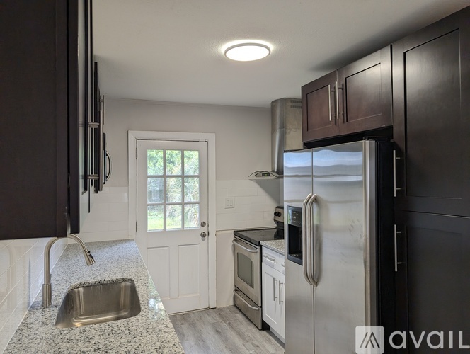 A kitchen with a stainless steel refrigerator and a white door.