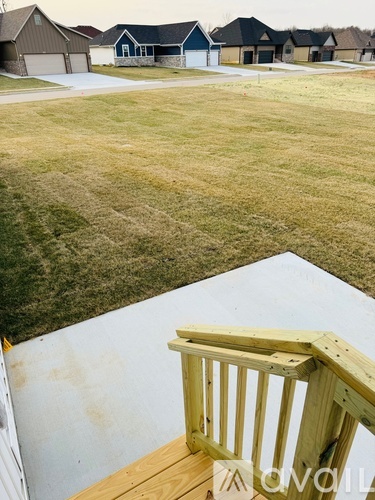 A wooden deck overlooks a grassy area with houses in the background.