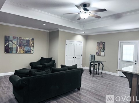 A living room with a black couch and a ceiling fan.