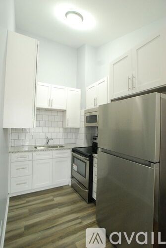 A kitchen with a stainless steel refrigerator and white cabinets.