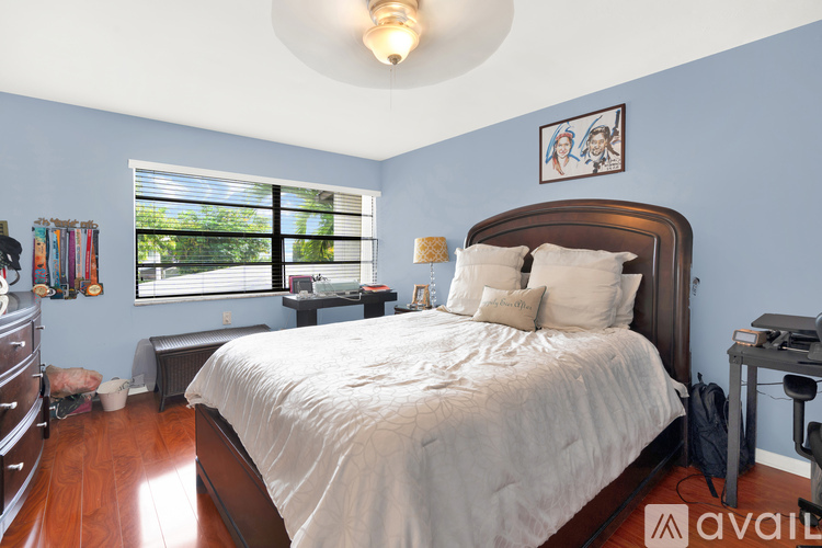 A bedroom with a large bed and a window with blinds.