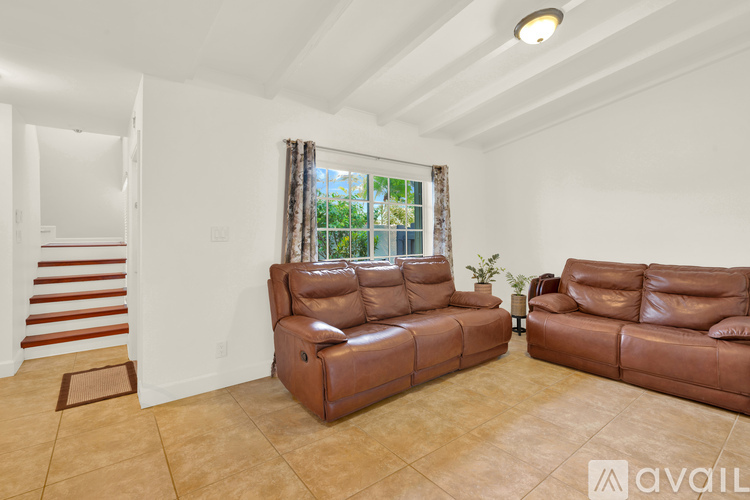 A living room with brown leather furniture and a staircase.