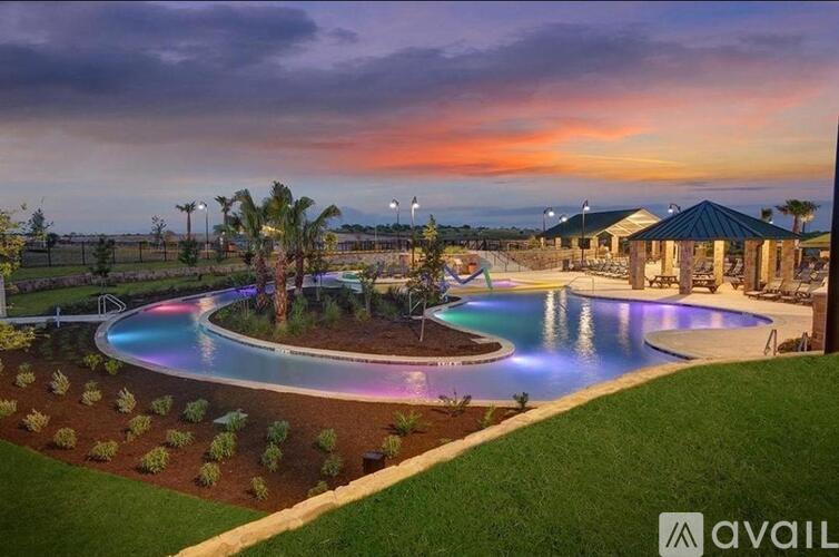A beautiful outdoor swimming pool area with a sunset sky in the background.
