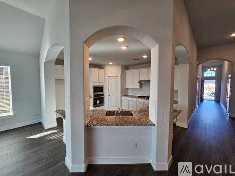 A spacious kitchen with a central island and arched doorways.