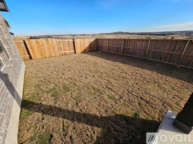 A backyard with a wooden fence and a grassy area.