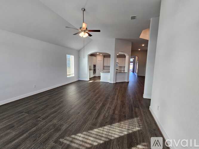 A spacious room with wooden floors and a ceiling fan.