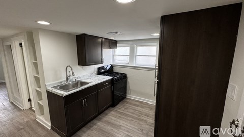 A kitchen with dark wood cabinets and a white sink.